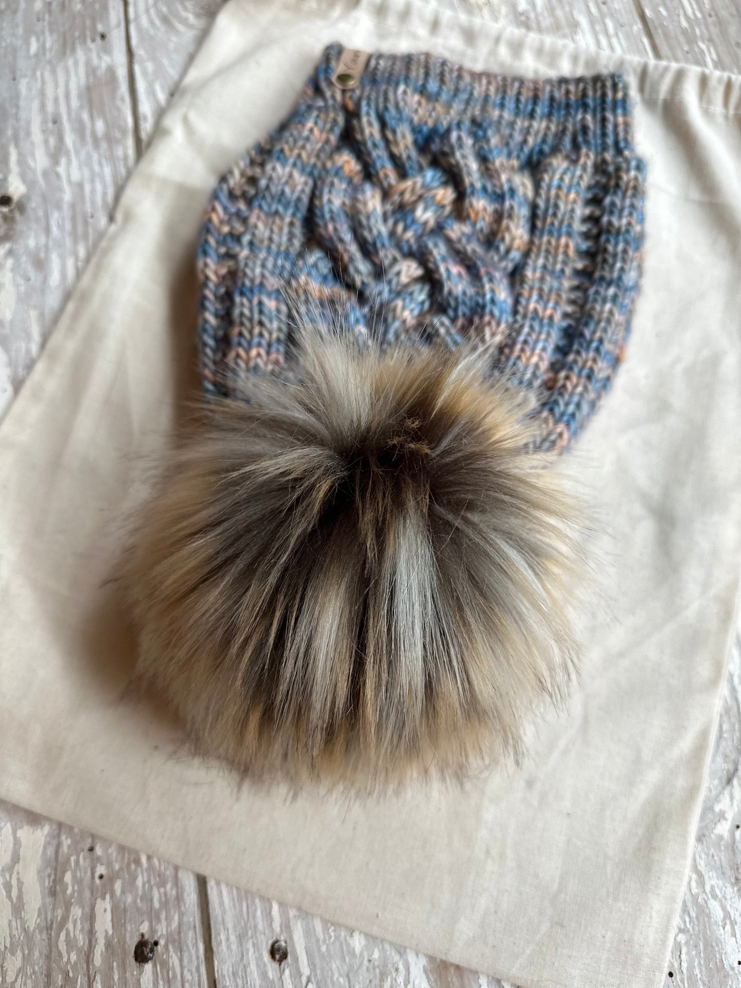Merino wool cable knit hat with faux fur pom